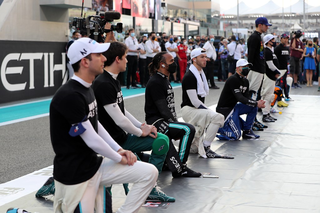 ABU DHABI, UNITED ARAB EMIRATES - DECEMBER 12: Lewis Hamilton of Great Britain and Mercedes GP and Pierre Gasly of France and Scuderia AlphaTauri take a knee in support of the We Race As One initiative on the grid before the F1 Grand Prix of Abu Dhabi at Yas Marina Circuit on December 12, 2021 in Abu Dhabi, United Arab Emirates. (Photo by Kamran Jebreili - Pool/Getty Images)